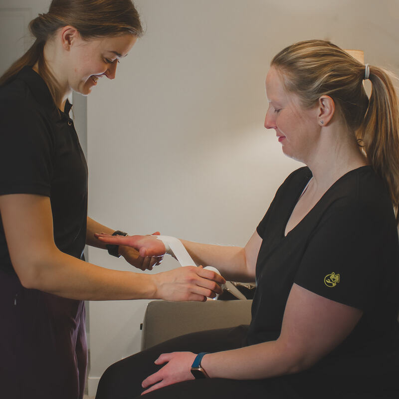 Erin is applying a prophylactic taping technique for an individual's wrist to provide support.